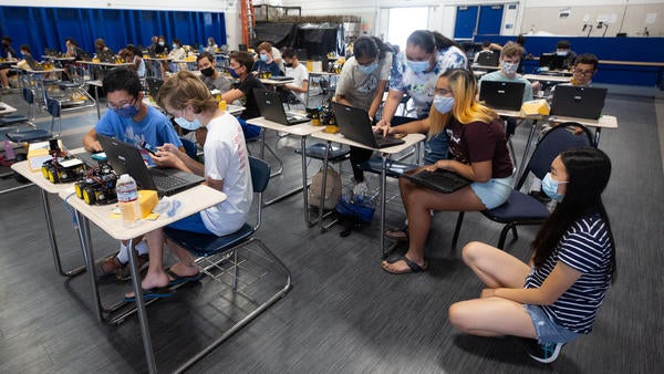 Groups of high school students work on their robotic projects.