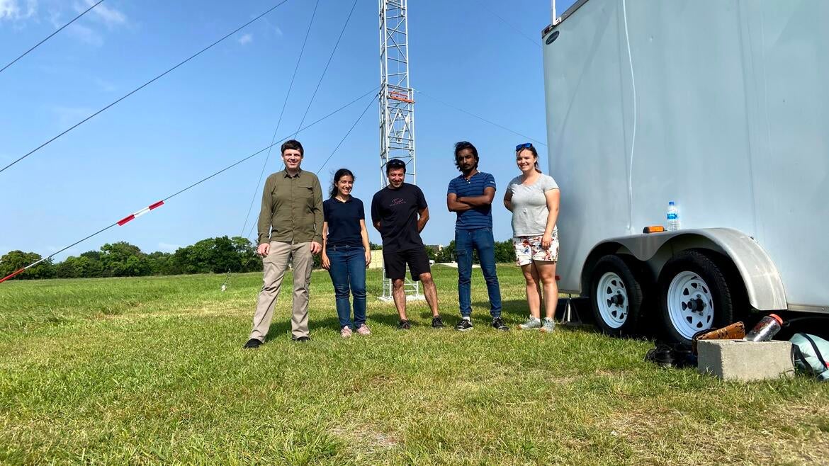 Markus Petters and members of the TRACER research group standing next to a flux tower in an open field in Texas.