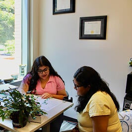 two women sitting in an office reviewing a printed document  