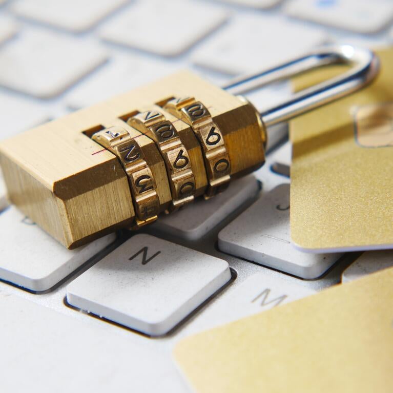 Padlock and two credit cards on top of laptop keyboard