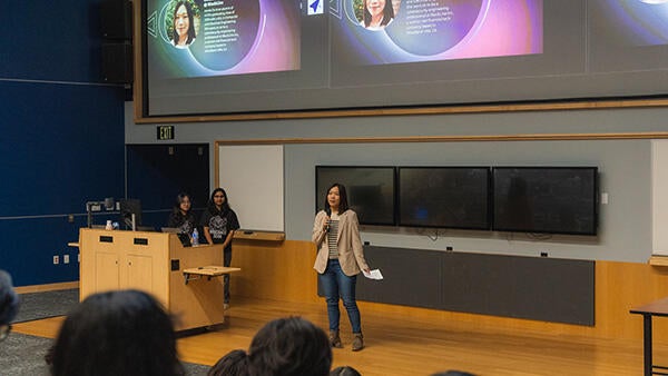 Photo of keynote speaker and BCOE alumni speaking onstage to Rose Hack participants.