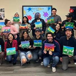 transfer students in the transfer center holding painted canvases