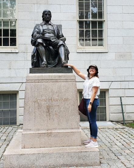 Woman rubs the foot of an outdoor statue of a man